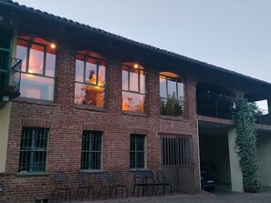 A brick building with multiple windows, a balcony, and outdoor seating. - Holiday Home 'Casa Centomila Volte Benvenuti' with Private Terrace (Tigliole)