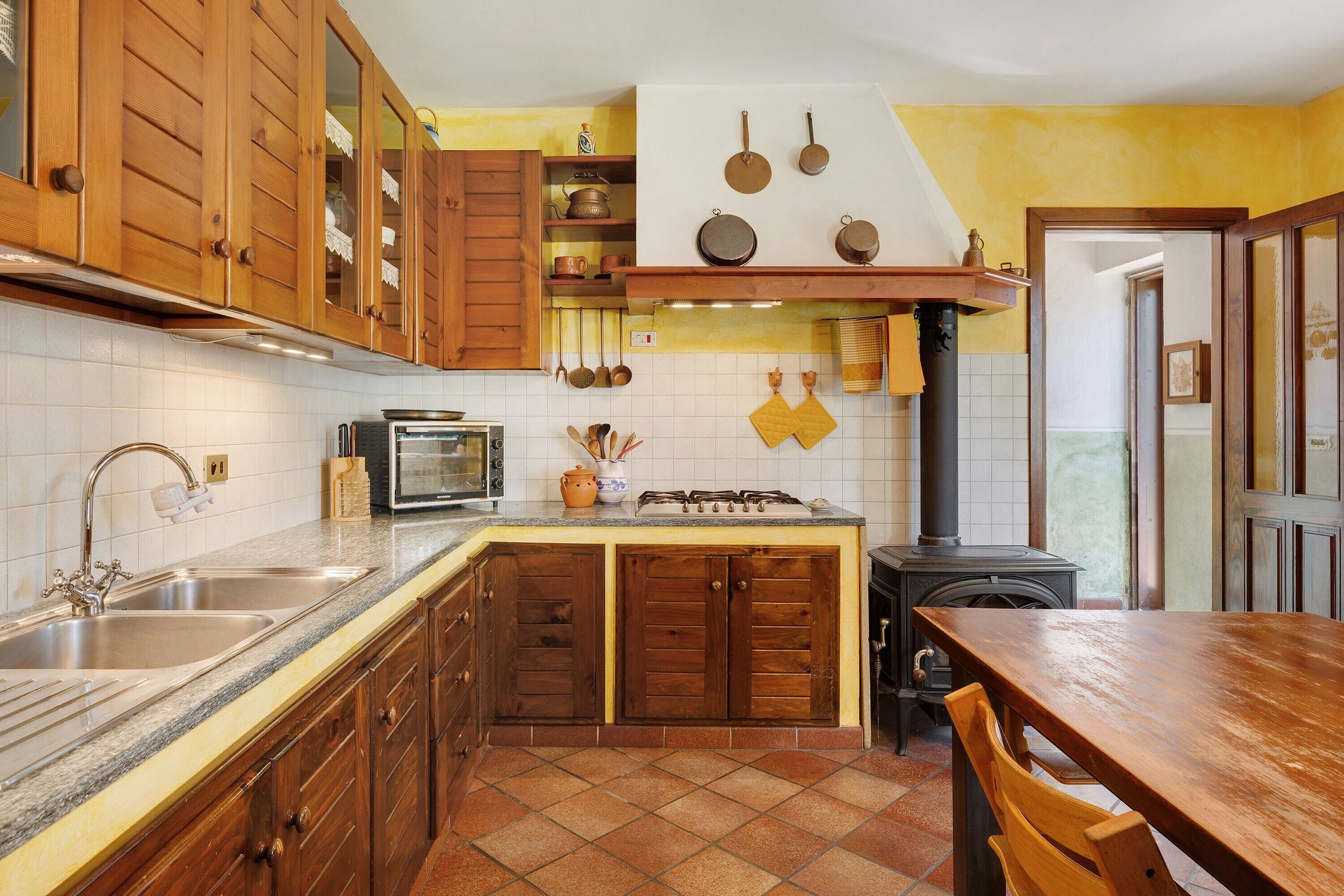A kitchen with wooden cabinets, a stove, a sink, and a tiled backsplash.