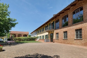 Un edificio de ladrillo con un patio empedrado, un balcón y una mesa con sillas.