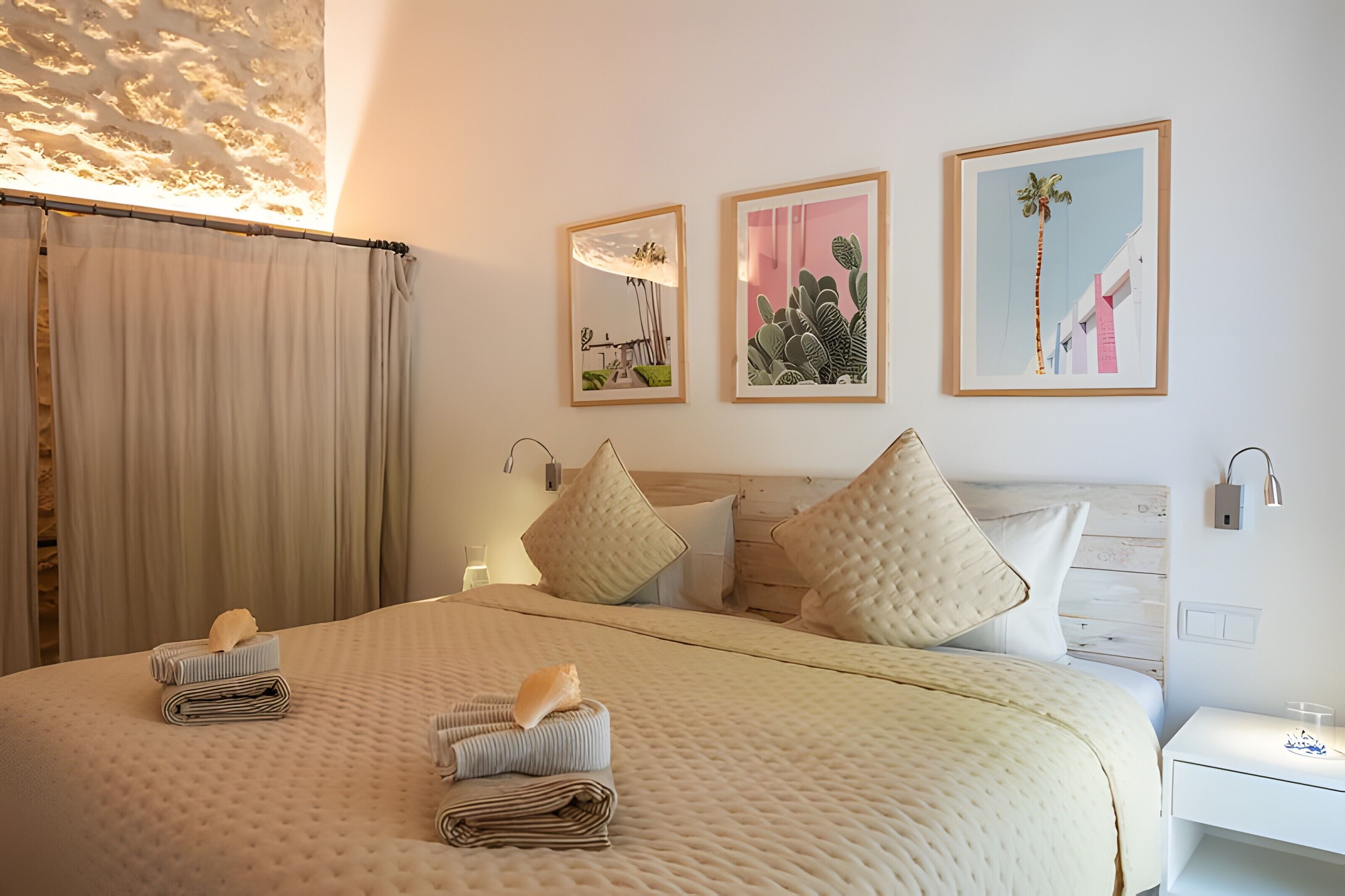 Een opgemaakt bed met kussens, een nachtkastje en wanddecoratie.