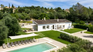 Una villa moderna con piscina, zona de estar exterior y jardín bien cuidado.