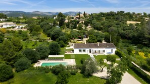 Ein modernes Haus mit Swimmingpool, umgeben von üppiger Vegetation und Bergen im Hintergrund.