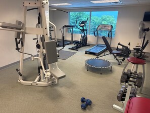 A gym with various exercise equipment, including a treadmill, elliptical, and free weights.