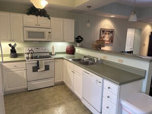 A kitchen with white cabinets, a microwave, stove, sink, and a dishwasher.