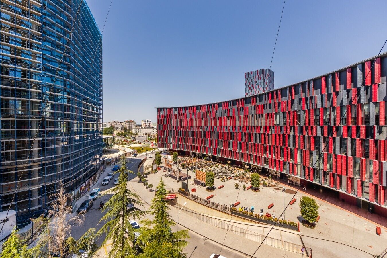 Um edifício moderno com fachada curva, área de estacionamento e céu claro.