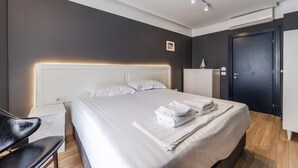 Ein modernes Hotelzimmer mit einem großen Bett, Nachttischen, einem Kleiderschrank und einem Schreibtisch.