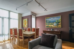 Una habitación con una mesa de comedor, sillas, un sofá, un armario y dos cuadros en la pared.