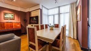 Ein Essbereich mit einem Holzpiano, einem Fernseher und einem großen Fenster mit Vorhängen.