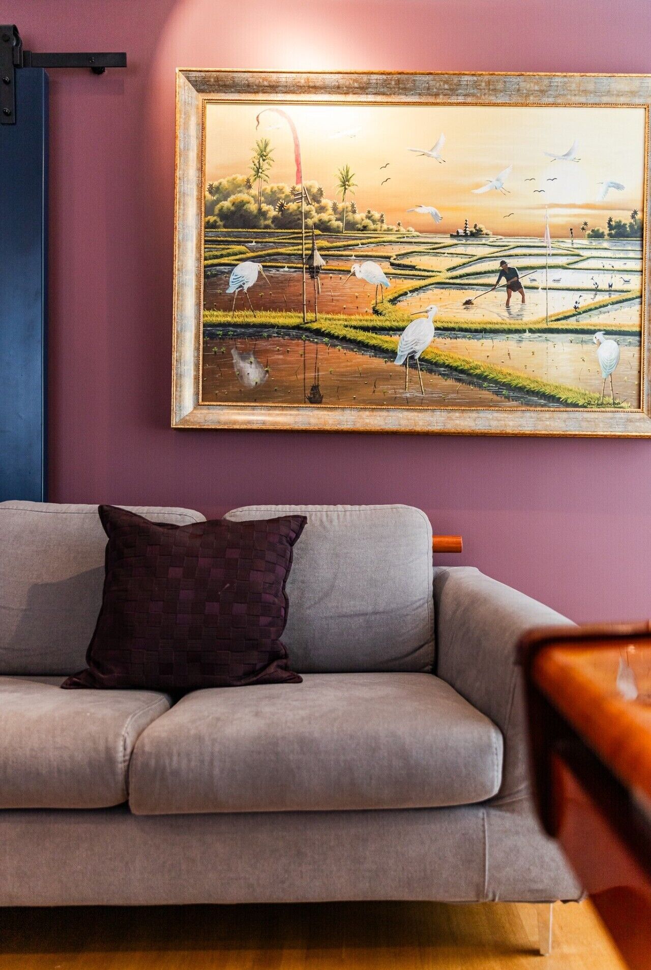 A living room with a sofa and a painting of a landscape.