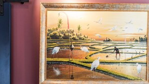 A living room with a sofa and a painting of a landscape.
