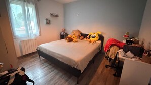 A bedroom with a bed, a desk, and a radiator. - Charming single-storey air-conditioned house, ideal for vacations in Provence (L'Isle-sur-la-Sorgue)