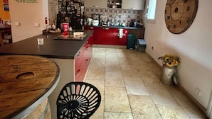 A spacious kitchen with a central island, a dining area with a wooden table and chairs, and a decorative wall clock. - Charming single-storey air-conditioned house, ideal for vacations in Provence (L'Isle-sur-la-Sorgue)