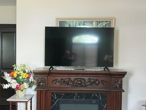 A flat-screen TV mounted on a wooden cabinet with a marble fireplace below. - Niagara River Idyll K *****
Luxurious King Ensuite (Fort Erie)