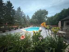 A swimming pool surrounded by potted plants and trees. - Niagara River Idyll 
Luxurious King Ensuite (Fort Erie)