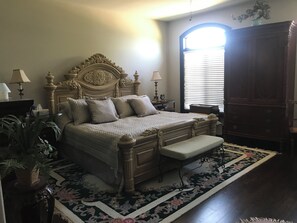 A bedroom with a large bed, bedside tables, a nightstand, a dresser, and a window with blinds. - Niagara River Idyll (Fort Erie)