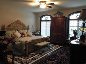 A bedroom with a bed, a nightstand, a dresser, a window with blinds, and a ceiling fan. - Niagara River Idyll (Fort Erie)