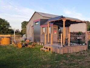 Un bâtiment rustique en bois doté d’une terrasse, de sièges extérieurs et d’un espace abrité.