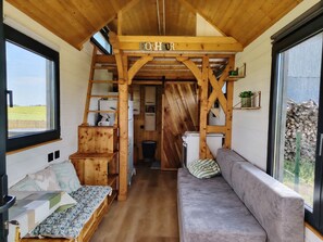 L’intérieur d’un chalet accueillant, avec un escalier en bois, un canapé et un lit.