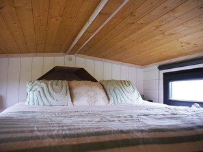 A wooden ceiling with a sloped design, a bed with patterned bedding, and a window on the right. - Family stay at the educational farm | Spa included | 1h30 from Paris (Villiers-Saint-Orien)
