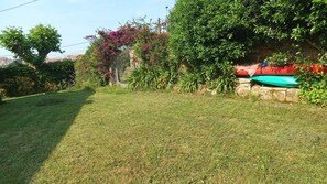 Une zone herbeuse bien entretenue, avec un mur en pierre et un objet rouge et vert placé sur le dessus.