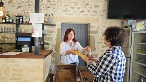 Eine Bar mit einer Steinsäule, einer Theke mit Speisekarte und Regalen mit Flaschen und Gläsern.