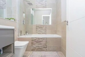 Un bany modern amb un box de dutxa de vidre, un lavabo blanc i un vàter.