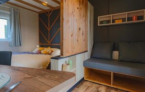 Une pièce comprenant un lit, un canapé, une table en bois et une étagère avec divers objets.