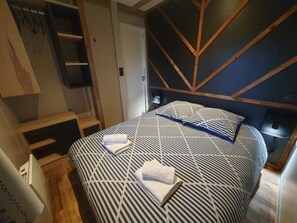 A bedroom with a bed, bedside tables, a wardrobe, and a mirror. - Chalet 3 étoiles - Piscine  - ccbgfcg (Saint-Père-en-Retz)