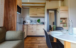 Une cuisine de taille réduite avec des meubles en bois, une table à manger avec des chaises et un canapé.