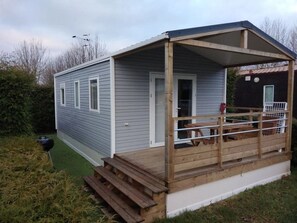 A small, single-story building with a covered porch and a door. - Camping 3 étoiles - Piscine  - ccbgedi (Saint-Hilaire-de-Riez)
