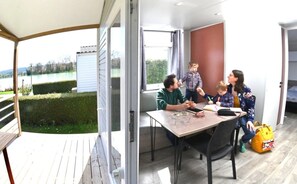 A modern interior with a dining area, large windows, and a view of the outdoors. - Camping 3 étoiles - Piscine  - ccbgedi (Saint-Hilaire-de-Riez)