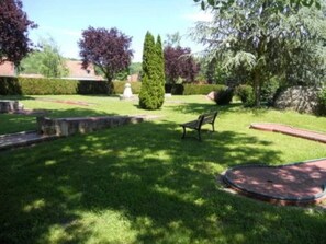 A well-maintained garden with a lawn, a circular stone feature, and a bench. - Camping 3 étoiles - Piscine  - ccbgedi (Saint-Hilaire-de-Riez)