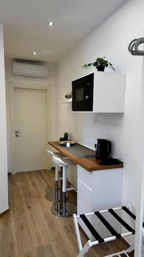 A compact kitchen with a microwave, coffee maker, and a small plant on the counter.