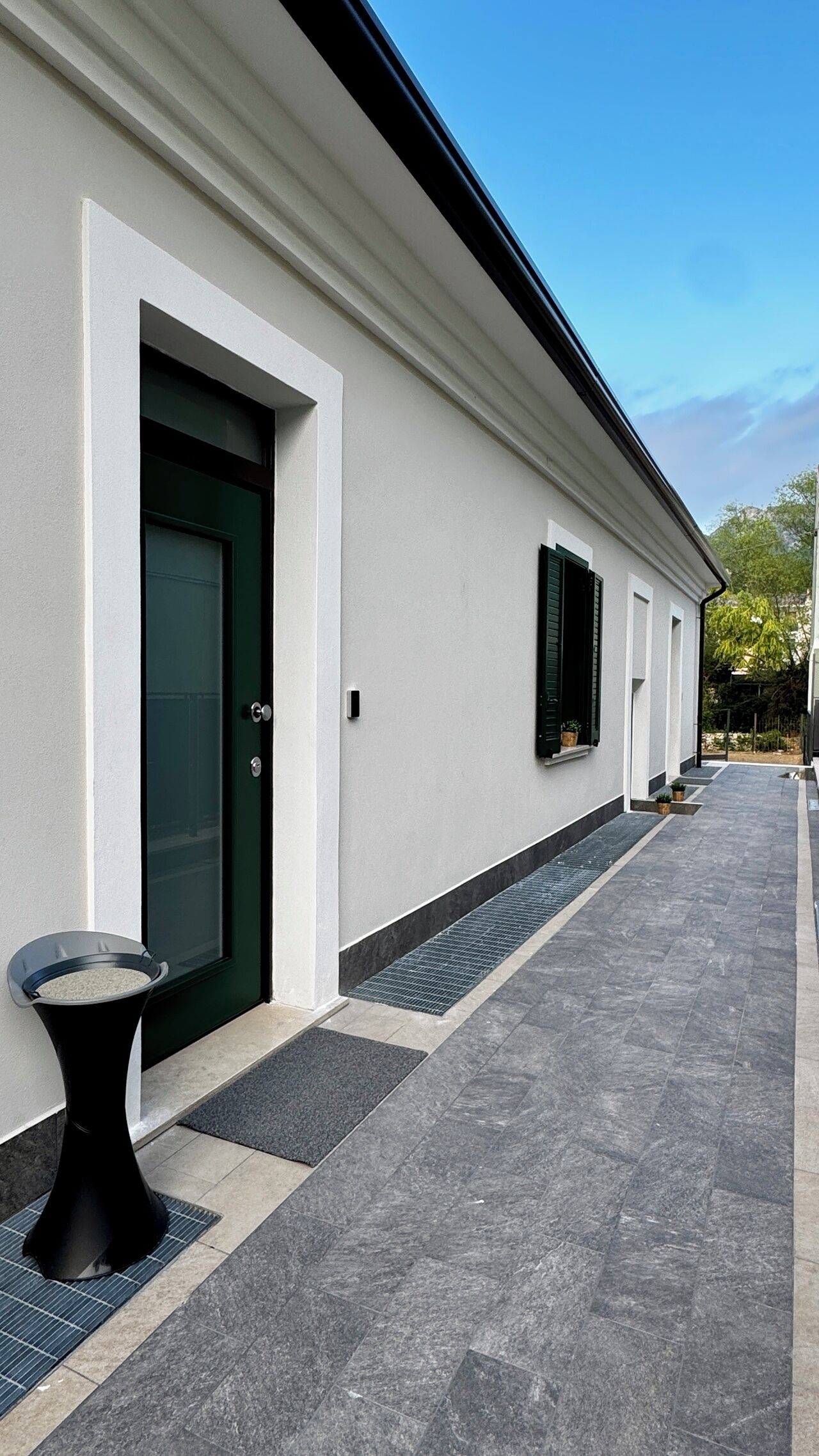 A building with a white exterior, a green door, and a black outdoor seating area.