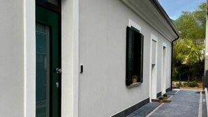 Un bâtiment à l’extérieur blanc, avec une porte verte et des fenêtres à cadre noir.