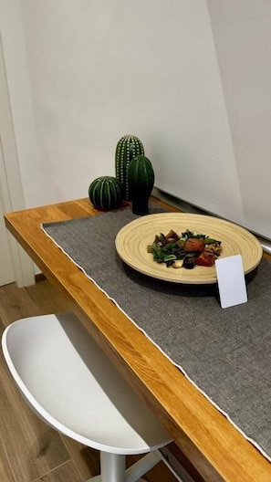 A dining table with a woven placemat, a plate of food, and two small potted plants.