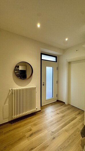 A hallway with a radiator, a round mirror, a door with a frosted glass panel, and a white door. - I Racconti del Fiume (Bussi sul Tirino)