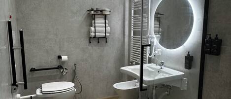 A modern bathroom with a glass shower enclosure, a round mirror, and a toilet with a bidet attachment.