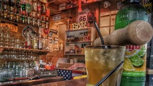 A bar setting with a glass of iced beverage, a bottle of soda, and a plate with pickles. - Camping 4 étoiles - Piscine  - ccbgce0 (Sorgues)