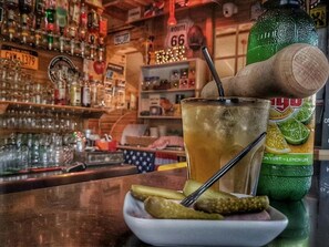 A bar setting with a glass of iced beverage, a bottle of soda, and a plate with pickles. - Camping 4 étoiles - Piscine  - ccbgce0 (Sorgues)