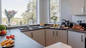 Eine moderne Küche mit einem großen Fenster, einer Spüle und einer Arbeitsplatte mit verschiedenen Gegenständen.