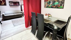 A modern living room with a sofa, TV, and artwork on the wall. - Staycation Studio Apartment (London)