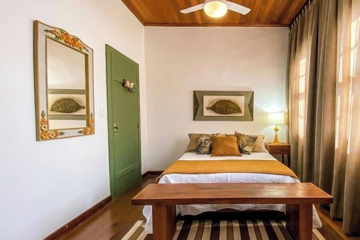 Une chambre à coucher avec un lit, un banc en bois, une porte verte et deux tableaux représentant des poissons, encadrés et accrochés au mur.