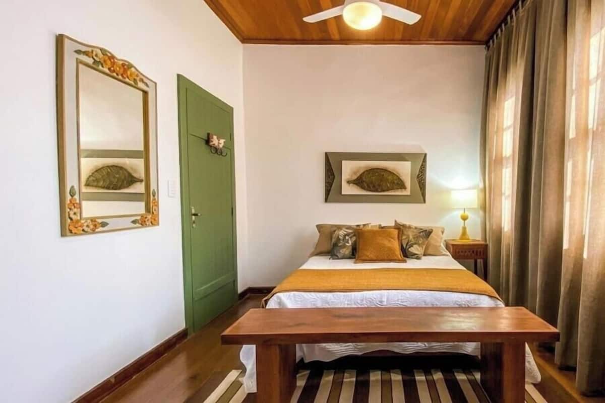 Une chambre à coucher avec un lit, un banc en bois, une porte verte et deux tableaux représentant des poissons, encadrés et accrochés au mur.
