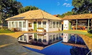 Una casa amb piscina, portes verdes i teulada enrajolada.