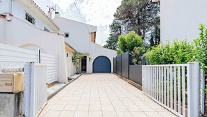 A gated driveway leading to a building with a dark blue door, white walls, and a tiled pathway. - Air-conditioned house with pool, sleeps 6 (Carcassonne)