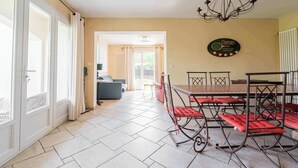 A dining area with a table and chairs, a chandelier, a tennis club sign, and a sofa in the background. - Air-conditioned house with pool, sleeps 6 (Carcassonne)
