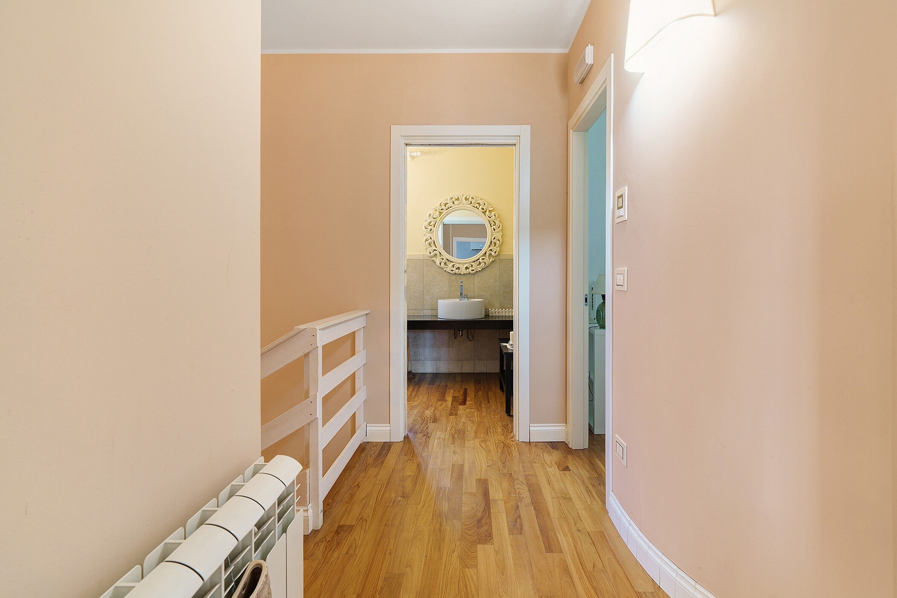 A hallway leading to a bathroom with a mirror and sink.