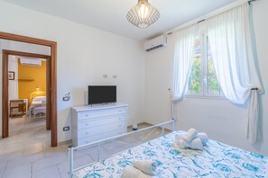 A bedroom with a bed, a TV, a dresser, an air conditioner, and a window with curtains. - Apartment 'Magnolia' with Pool, Wi-Fi and Air Conditioning (Arenella)