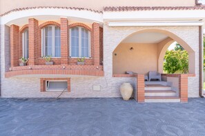 A building with a brick facade, large windows, a covered patio area, and a large vase. - Apartment 'Magnolia' with Pool, Wi-Fi and Air Conditioning (Arenella)